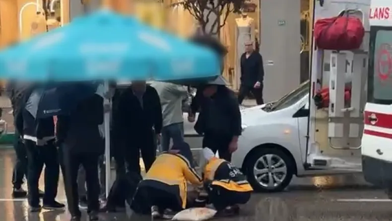 Otomobilin çarptığı yaralıyı yağmurdan korumak için şemsiye tuttular