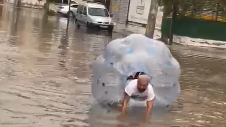 Sağanakta suyla dolan caddede içine girdiği büyük şeffaf balonla ilerledi